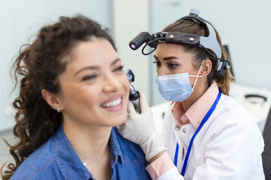 ENT specialist examining a patient's ear with an otoscope
