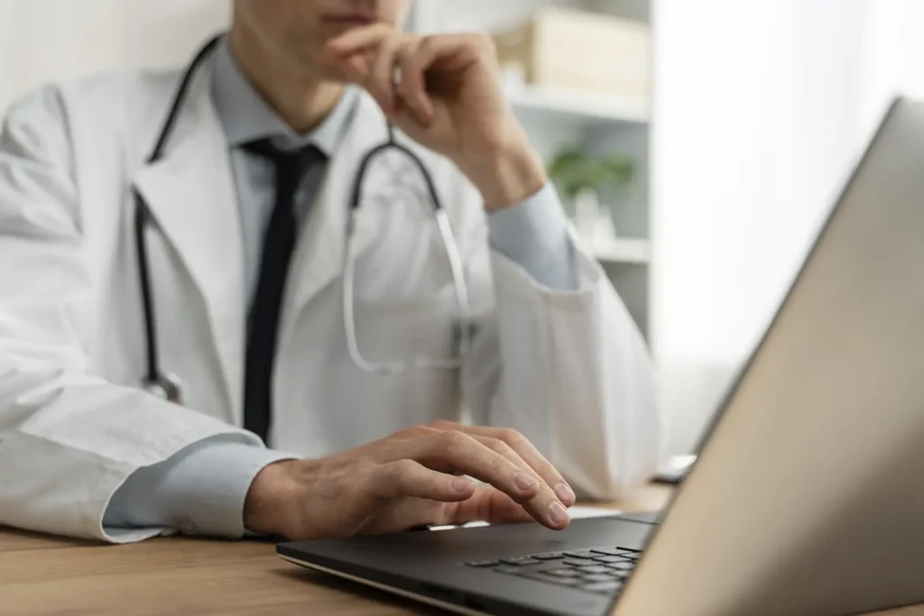 Doctor working on a laptop at a desk.