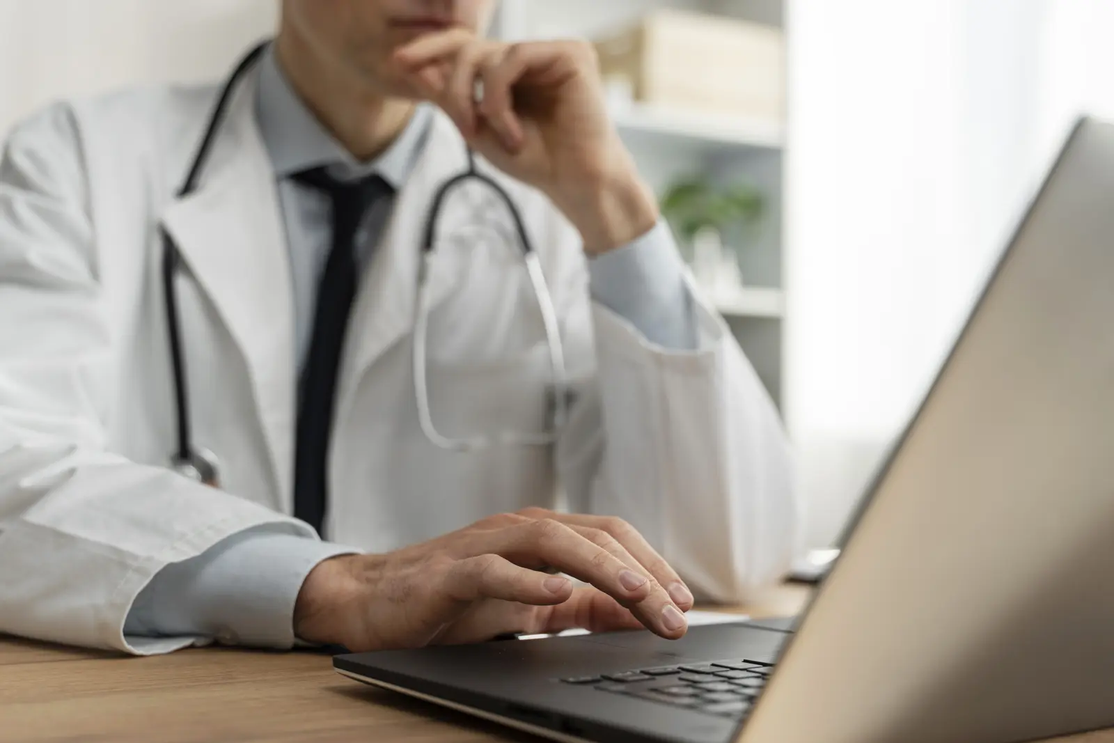 Doctor working on a laptop at a desk.