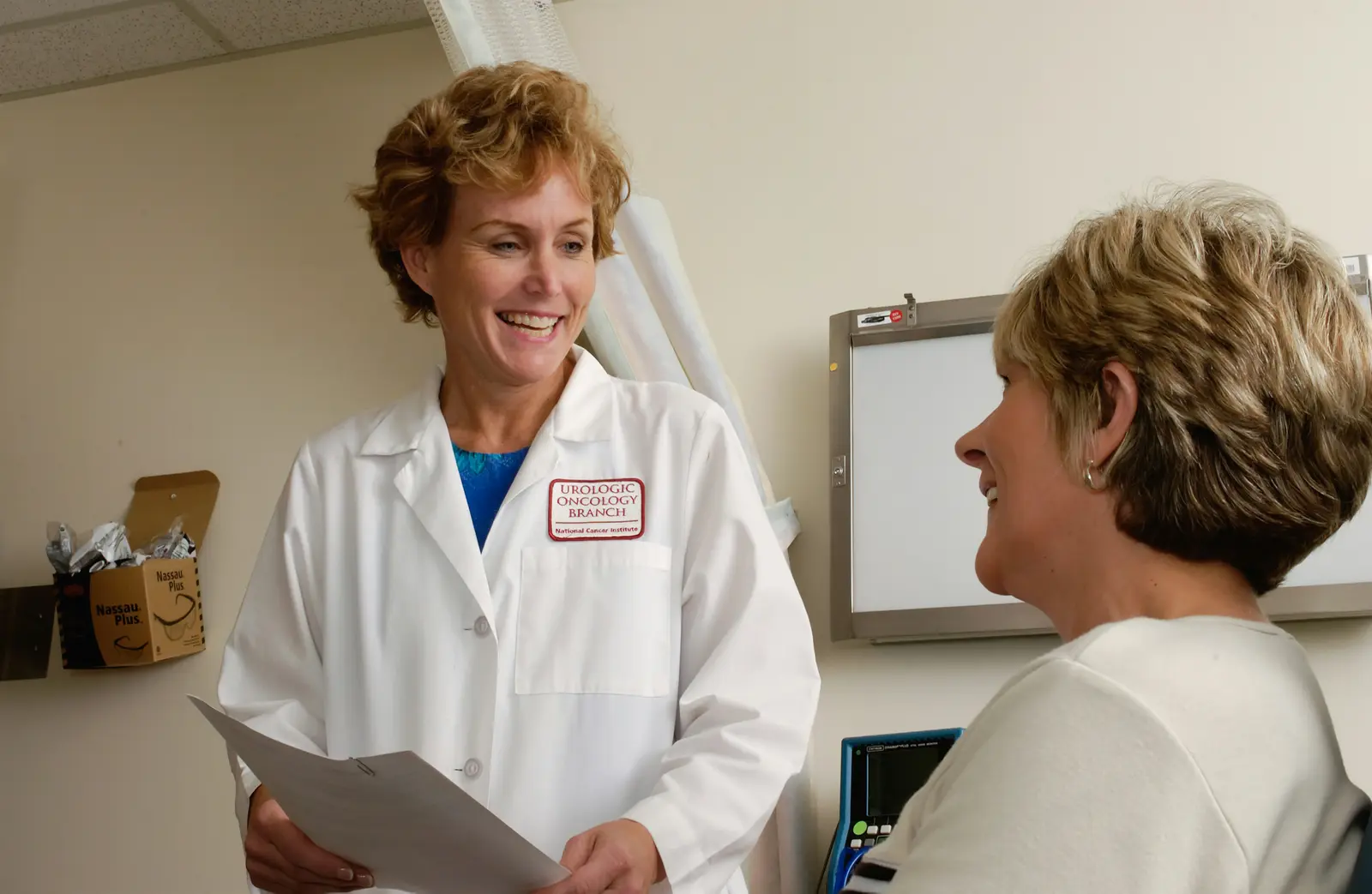 Doctor and a woman discussing paperwork during a consultation.