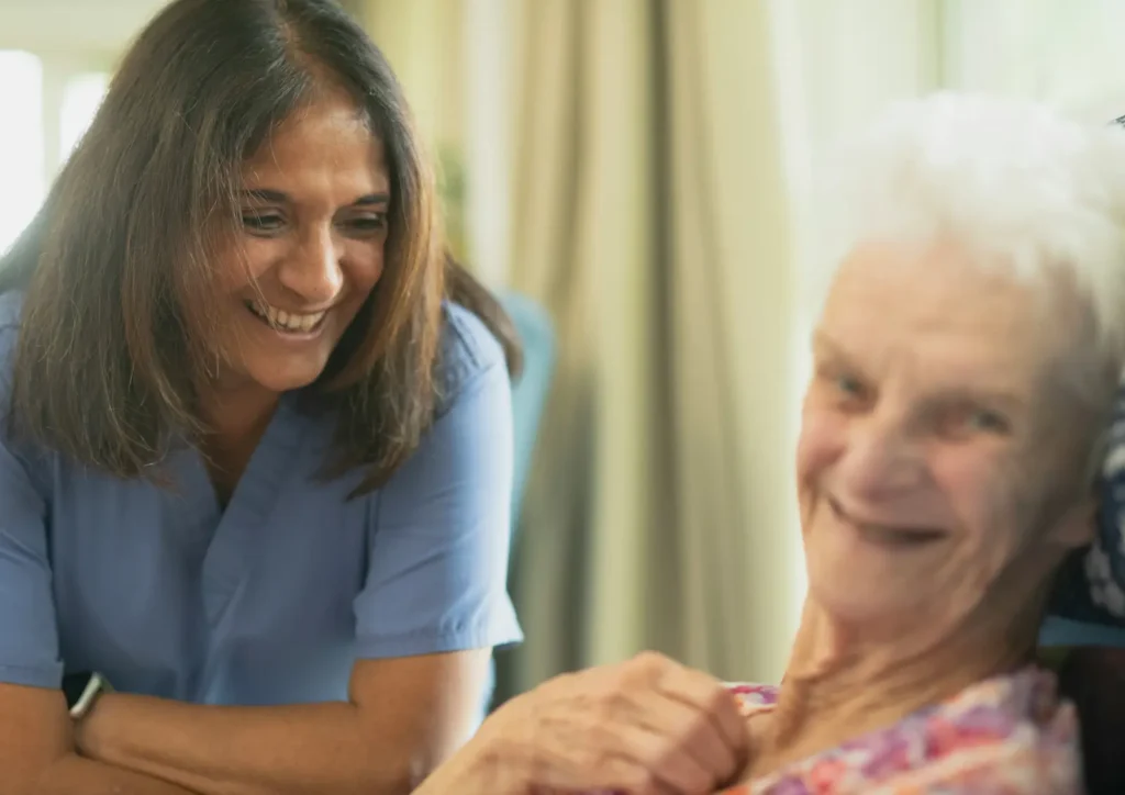 Caregiver sitting beside an older woman during a care visit.
