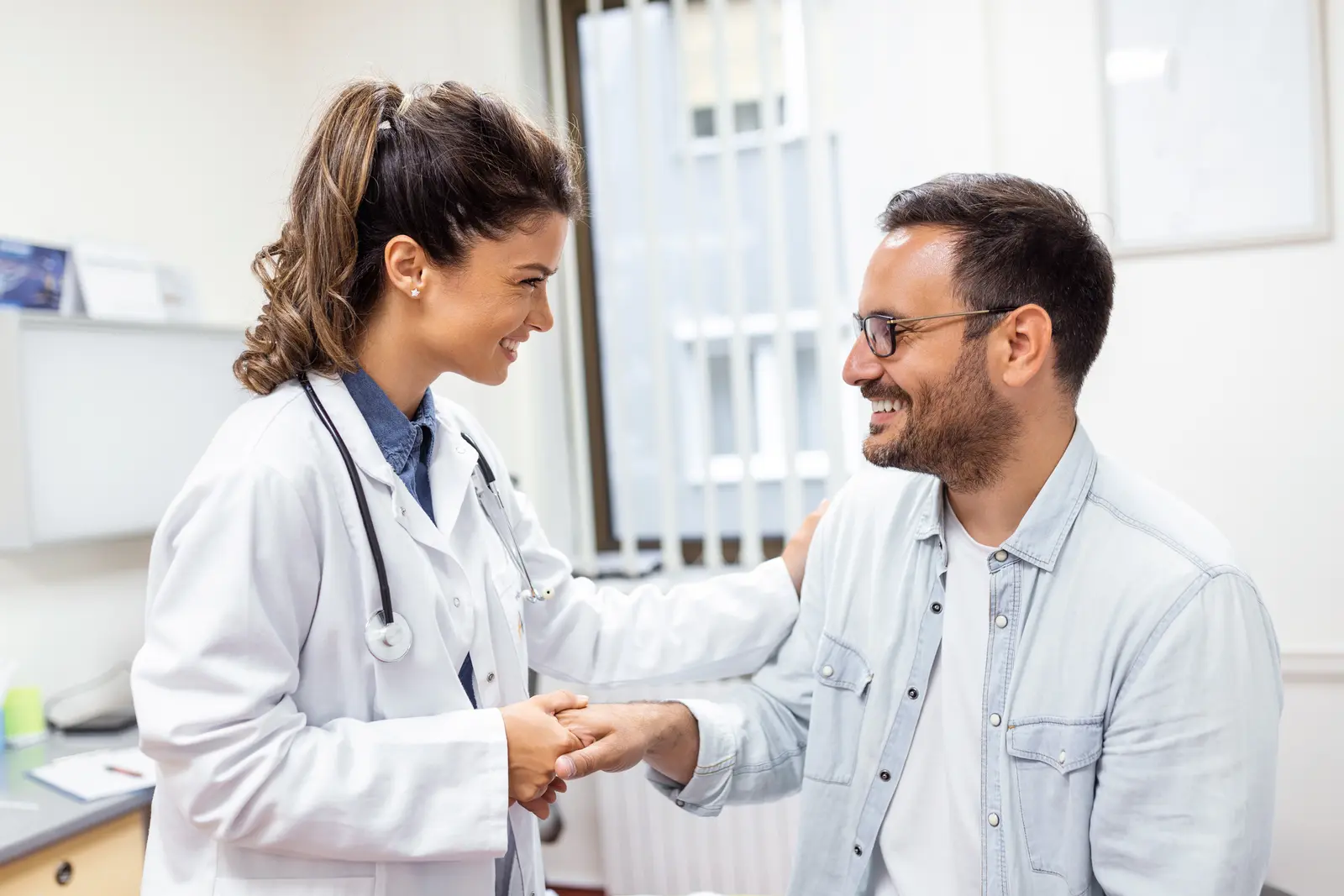 Doctor shaking hands with a man during a consultation.
