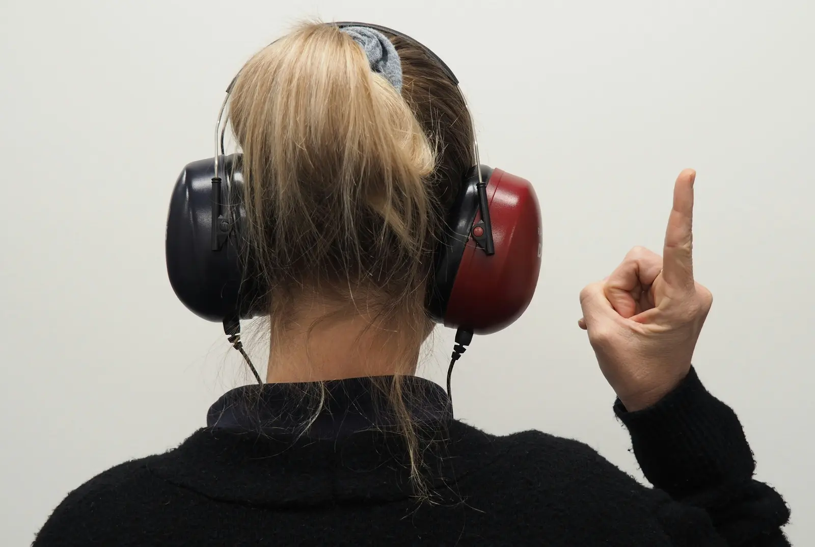 Person wearing hearing-test headphones and raising a finger.