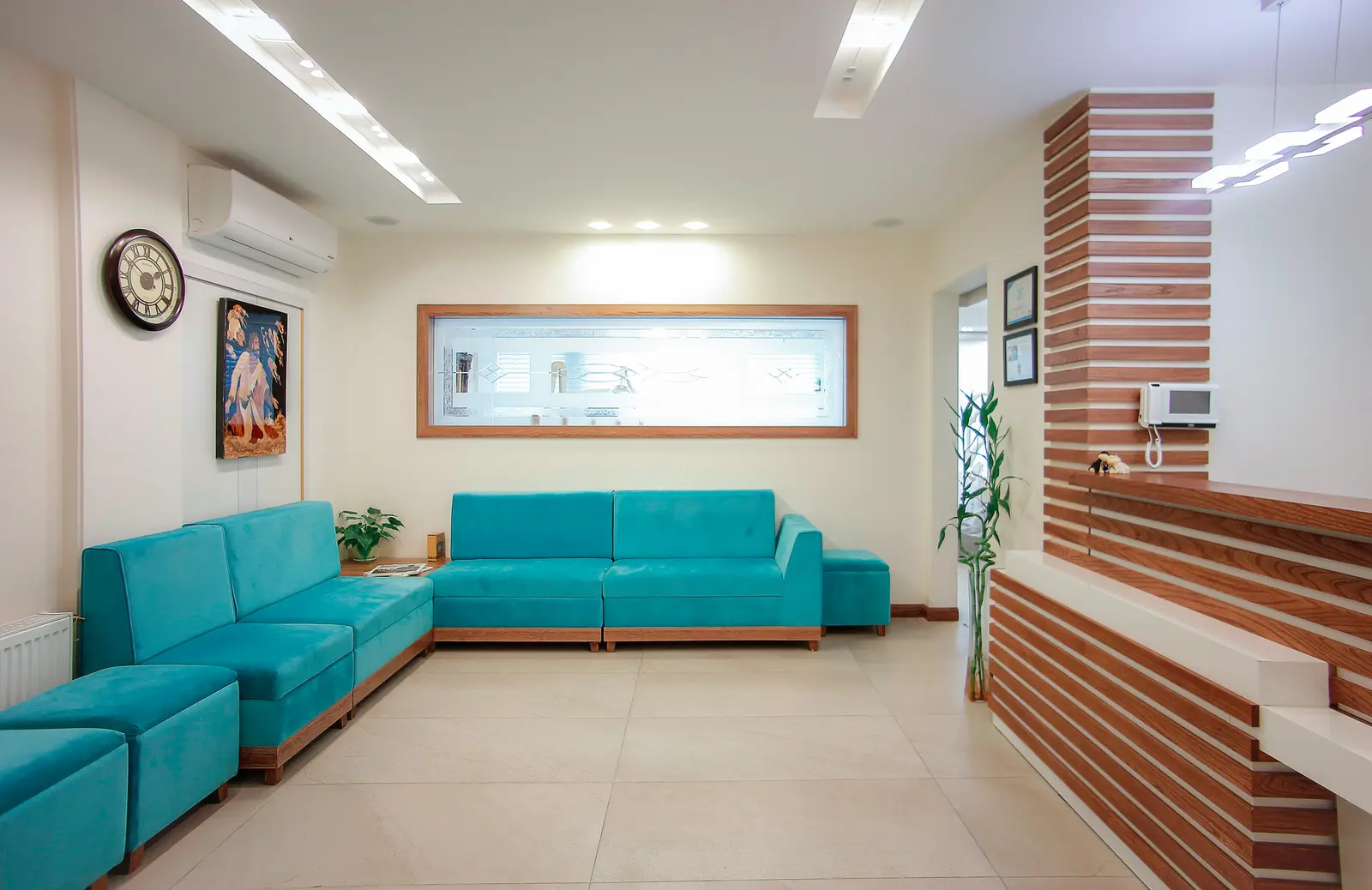 Clinic waiting room with turquoise seating and a potted plant.