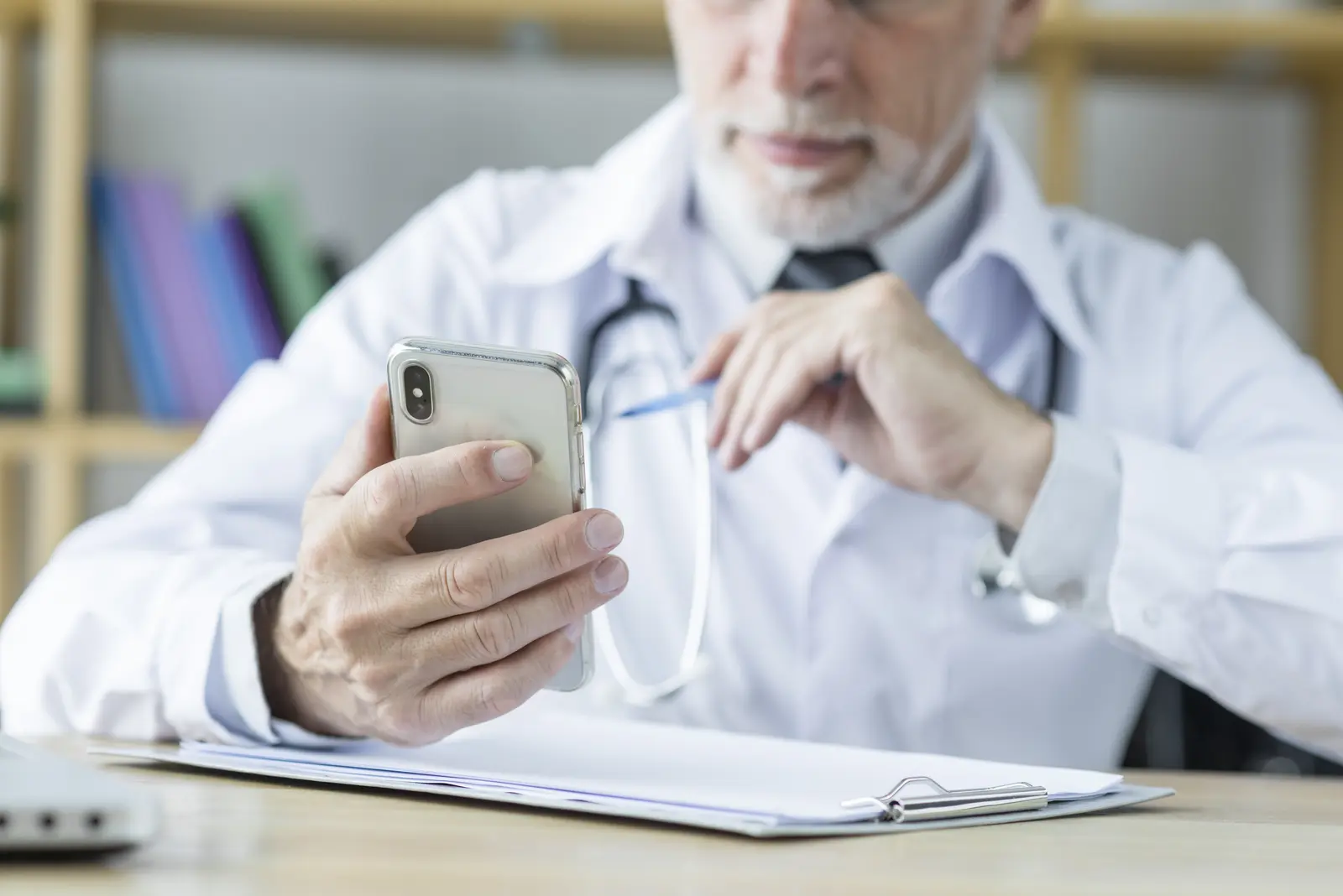 Doctor using a smartphone at a desk.